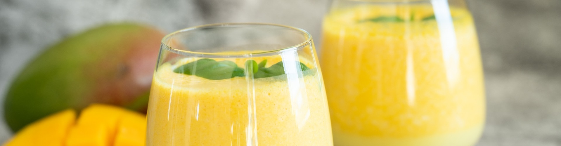 Fresh mango lassi in glasses on grey background with copy space.
