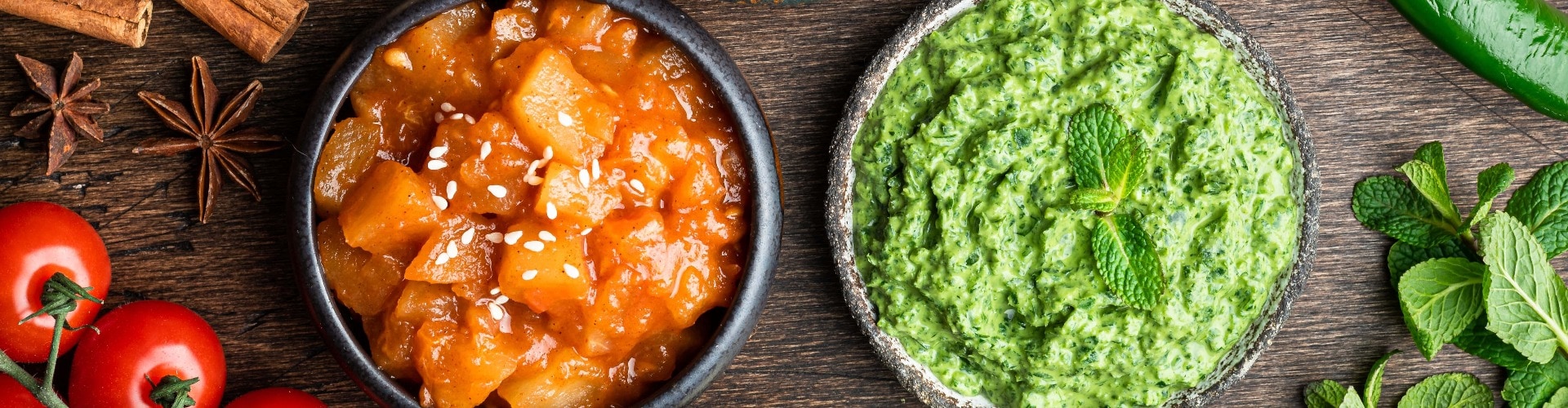 Indian chutney set in bowls on wooden background, top view